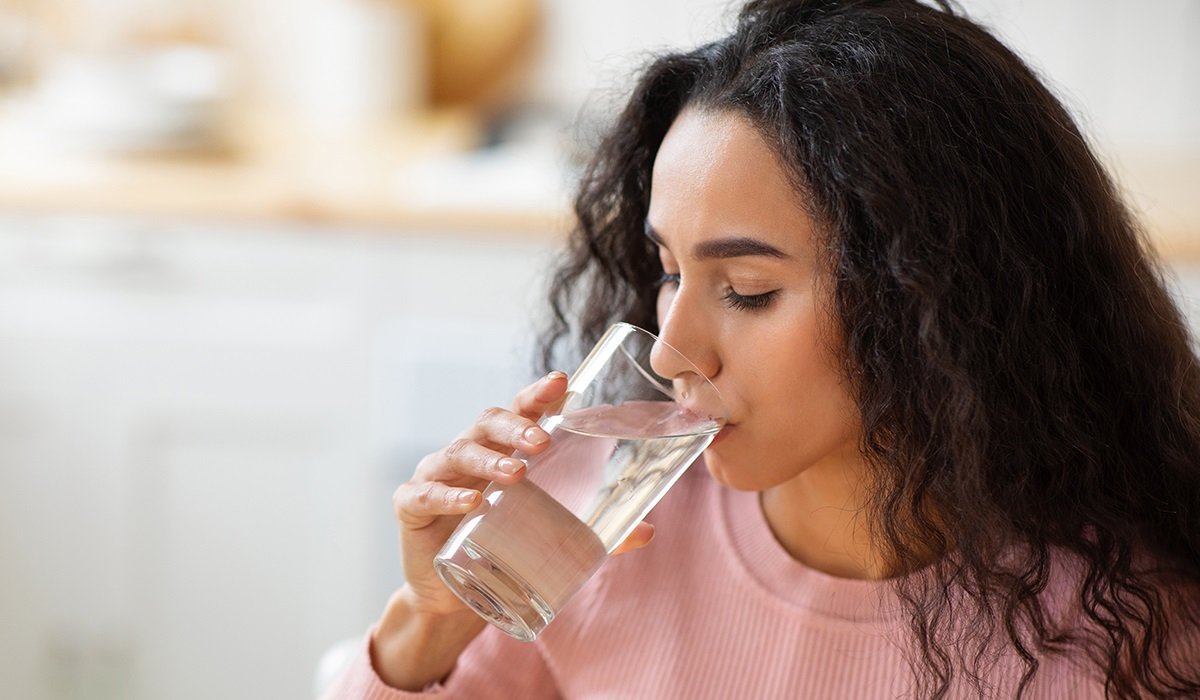 healthy-liquid-beautiful-brunette-woman-drinking-mineral-water-from-glass-kitchen